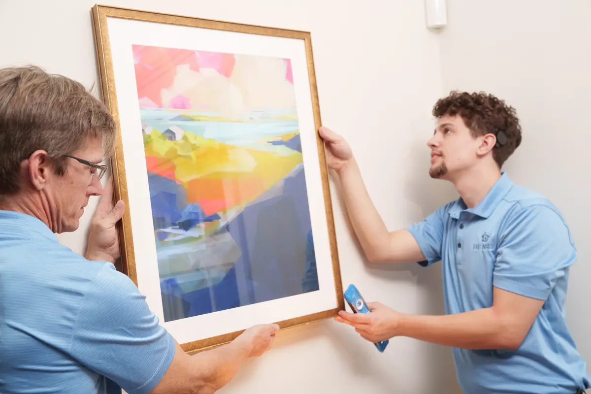 Two Henry Homes technicians hanging a framed painting